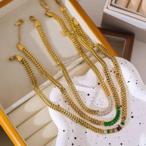Detailed close-up of gold layered chains with emerald and clear zircon rectangle pendants