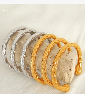 Detailed view of hammered texture on gold and silver stainless steel open bangles