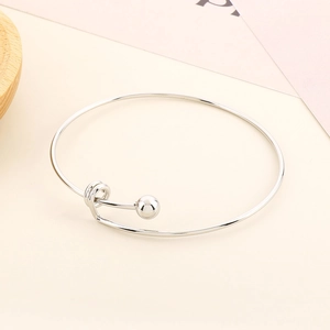 Detail of adjustable silver beaded steel bracelet with ball end design on warm background