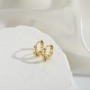 Macro de boucles d'oreilles créoles dorées serties de zircons sur pierre texturée