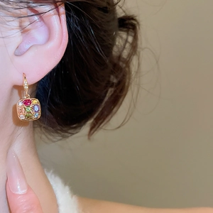 Detail of square earrings with colorful gemstones and small diamonds in golden finish