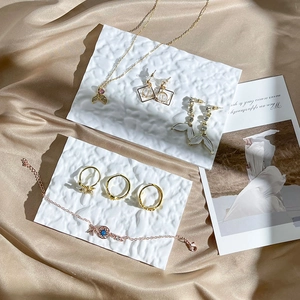 Elegant gold jewelry set with necklace and rings on silk background and textured stands