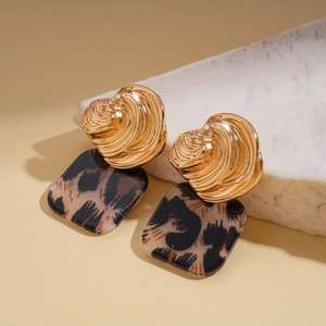 Detailed close-up of golden spiral metal earrings with leopard print resin square pendants
