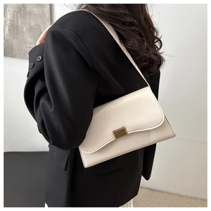 Close-up of vintage creamy white shoulder bag with textured gold clasp on black blazer
