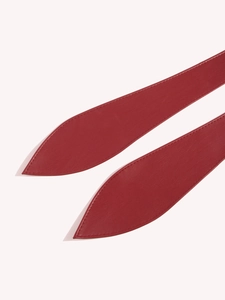 Detail of red leather waist belt with fine stitching and pointed leaf-shaped ends