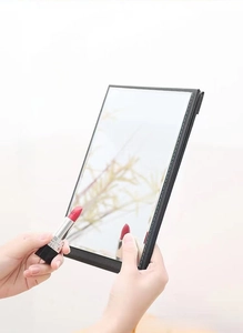 Detail of portable folding makeup mirror with black faux leather texture and white stitching