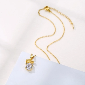 Elegant gold bow necklace with a pear-shaped zircon drop pendant on a minimalist base