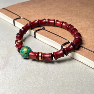 Bracelet en bois de santal bambou avec perle dorée verte sur carnet vintage
