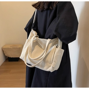 Detail of white corduroy tote bag showing thick ribbed texture and side zipper pocket