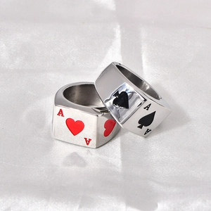 Macro detail of two silver poker Ace rings on white silk featuring heart and spade designs