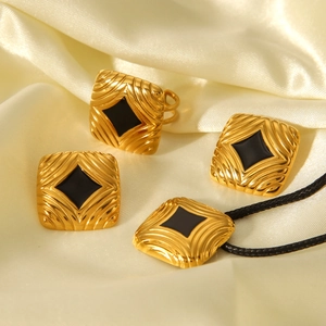 Detail of 18K gold stainless steel jewelry set with black enamel and wavy textures
