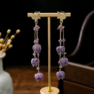 Close-up of long purple tassel earrings with golden butterfly and floral beaded details