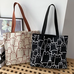 Detail of canvas tote bags featuring artistic cat line drawings in beige and black colors
