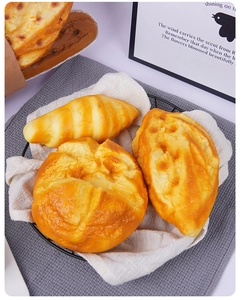 Primer plano de modelos realistas de cruasanes y pan de PU en una cesta de metal negra