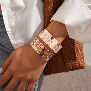 Vue détaillée de larges bracelets extensibles émaillés à fleurs avec finitions or et argent