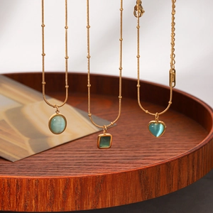 Detailed close-up of three gold necklaces featuring heart, oval and square blue cat-eye pendants