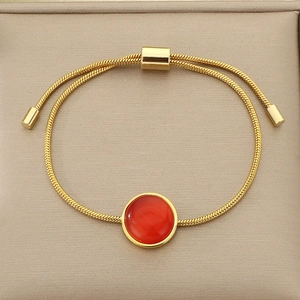 Détail du bracelet chaîne serpent dorée avec pierre oeil-de-chat rouge et fermoir ajustable