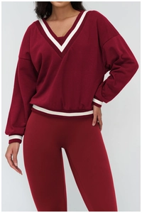 Detail of red V-neck sweatshirt featuring contrasting white stripes on collar and cuffs