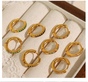 Macro detail of gold-plated earrings with colorful zircon inlays in a jewelry box