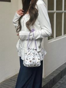 Quilted fabric drawstring bag detail with cartoon illustration and purple woven cord