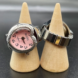 Creative heart-shaped pink dial finger watch with silver metal elastic band on wood stands