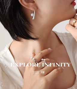 Detail view of pearl earrings and rings on model with Explore Infinity text