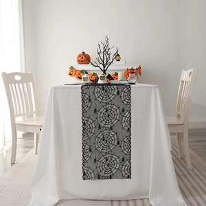 Halloween black lace spider web table runner set on a festive dining table with pumpkins