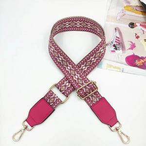 Macro shot of rose pink jacquard bag strap with geometric patterns and gold metal clips