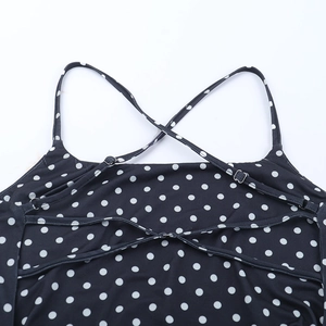 Détail des bretelles croisées réglables et boucle métallique sur robe noire à pois