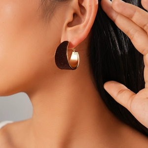 Close-up of model wearing C-shaped earrings with dark brown flocking texture
