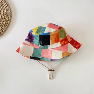 Detail of colorful canvas bucket hat featuring geometric blocks and adjustable wind cord