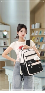Girl wearing black and white school backpack with cloud pendant in library setting