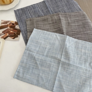 Detailed view of three minimalist linen placemats with stripe and grid patterns