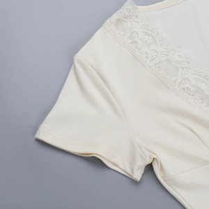 Détail de haut en maille blanc crème montrant la bordure en dentelle et le col en V