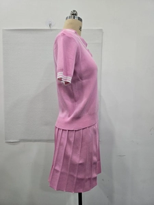 Détails du polo en maille rose avec rayures aux poignets et jupe plissée assortie