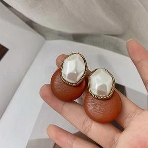 Macro shot of vintage round brown faux leather earrings with pearl and golden edge detailing