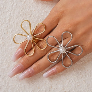 Detail of minimalist gold and silver flower rings with pearls worn by a model