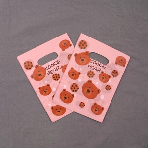 Detail of pink plastic gift bag with cute cookie bear pattern and top handle