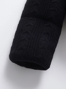 Macro shot of chunky black cable knit texture and ribbed cuff on a winter jacket sleeve