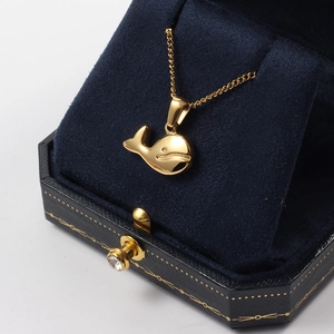 Gold whale pendant necklace displayed in a premium navy blue velvet hexagonal jewelry box