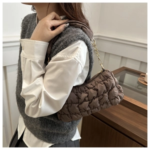 Close-up of brown bubble quilted bag with gold chain strap on grey knit vest