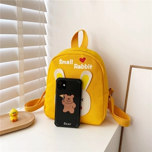 Mini yellow canvas toddler backpack with rabbit ears shown next to a smartphone