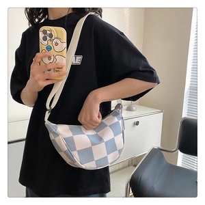 Detail of blue and white checkered knit dumpling bag showing woven texture and strap