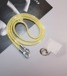 Detail of yellow sparkling rhinestone phone lanyard with silver clasps and clear pad on gray desk