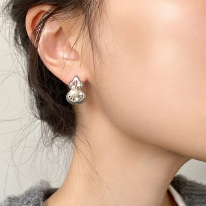 Close-up of hollow gourd stud earring with pearl and cubic zirconia on model ear