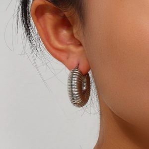 Close-up of silver stainless steel hoop earrings with horizontal ribbed diamond facets