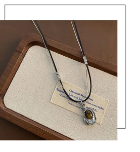 Macro shot of double-layer necklace with brown tiger eye stone and silver pendant