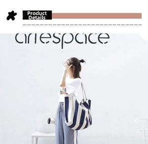 Detail view of large striped canvas tote bag worn by a model in a minimalist setting