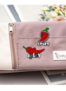 Detail of red enamel chili pins with sparkling rhinestones and 'SPicy' text on fabric