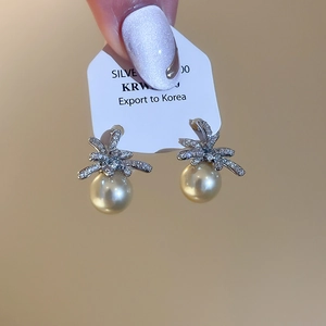 Close-up of elegant flower pearl earrings with silver needle and sparkling zircon
